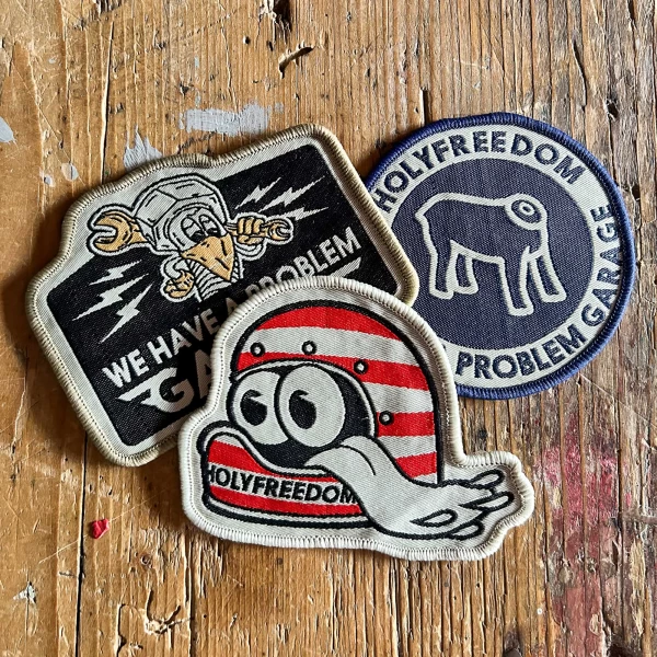 Front view of the Holyfreedom Garage Box with three original motorcycle patches.