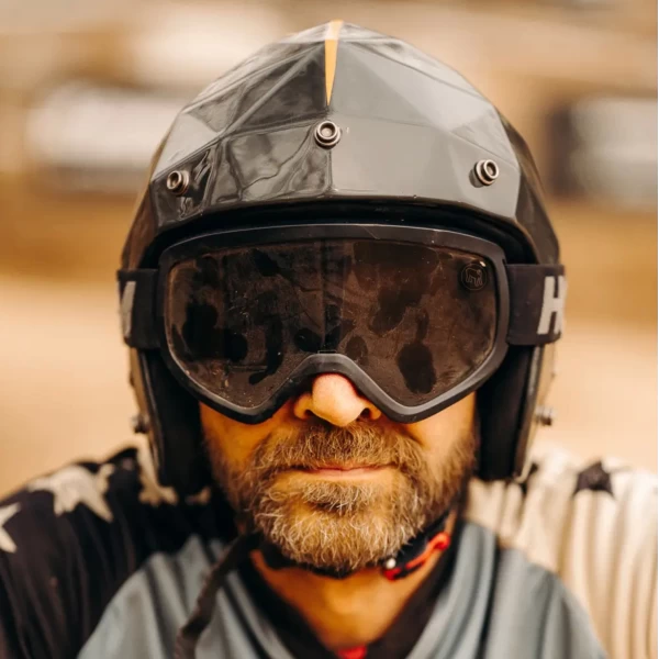Occhiali moto vintage indossati con casco jet e giacca cafe racer per uno stile urbano forte.