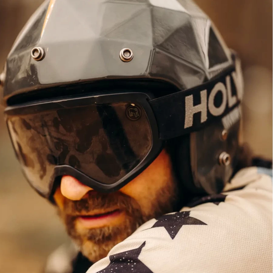 Occhiali moto vintage indossati con casco jet e giacca cafe racer per uno stile urbano forte.
