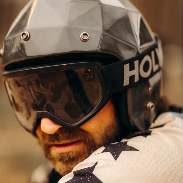 Occhiali moto vintage indossati con casco jet e giacca cafe racer per uno stile urbano forte.