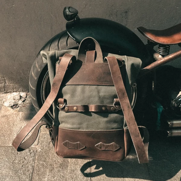 Detail of the green backpack roll-top closure and metal plate mounting system