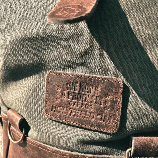 Detail of the green backpack roll-top closure and metal plate mounting system