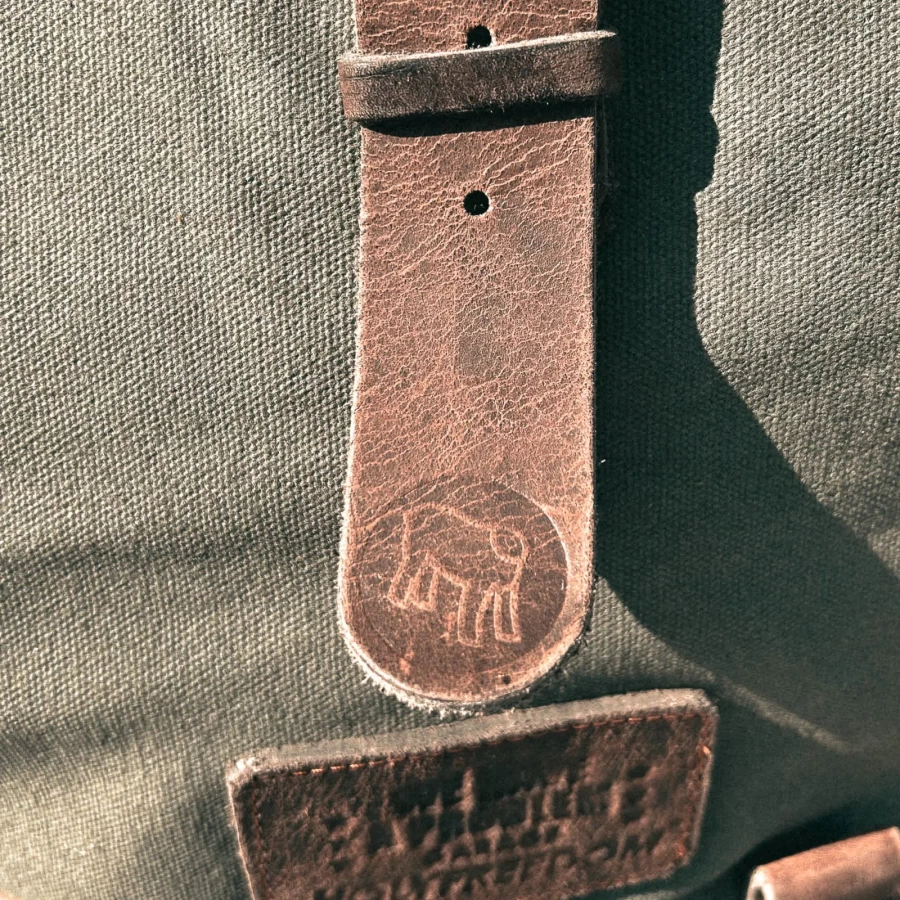 Detail of the green backpack roll-top closure and metal plate mounting system